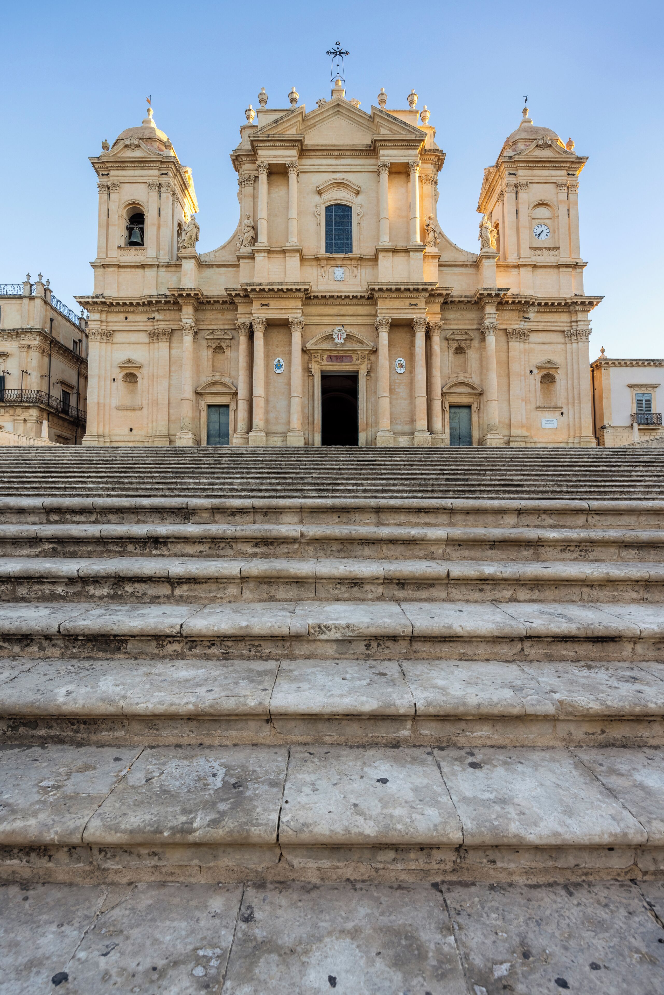 A grand historical building with a central dome, two smaller domes, and a bell tower.