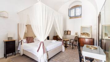 A bedroom with a four-poster bed, a small table, and a chair.