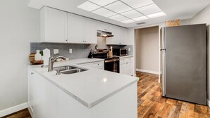 Een moderne keuken met witte kastjes, een roestvrijstalen koelkast en een centraal keukenblok met een spoelbak.