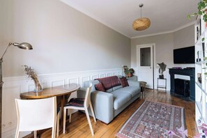 A living room with a sofa, a small table, a lamp, a fireplace, and a television.
