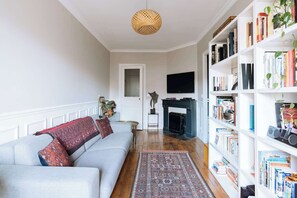 A living room with a sofa, a fireplace, a bookshelf, and a television.