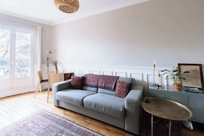 A living room with a sofa, a small table, a cabinet, a lamp, and a plant.