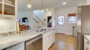 Cucina con piani in marmo, elettrodomestici in acciaio inossidabile e illuminazione a sospensione.