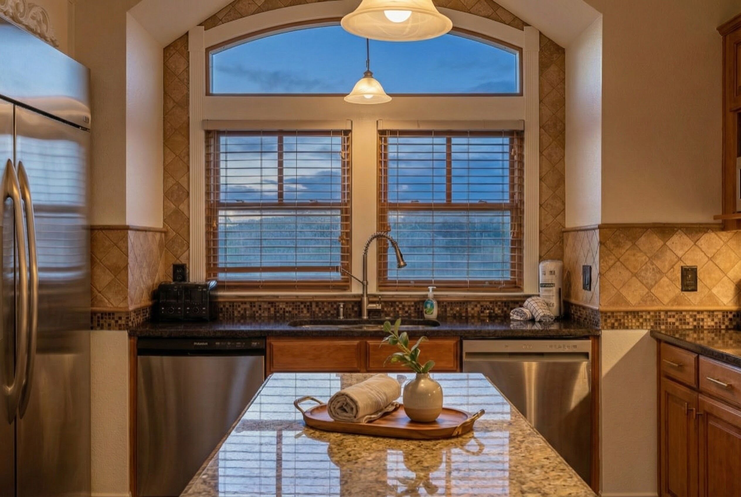 A kitchen with a large island, double sink, and a view of the sky through the window.
