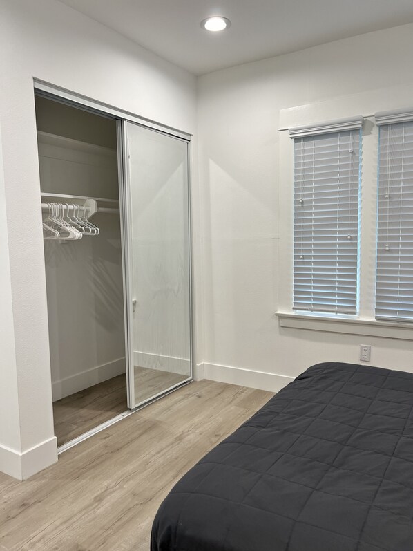Un dormitorio con una cama, un armario con puerta corrediza y una ventana con persianas.