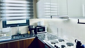 Una cocina moderna con estufa integrada, microondas y ventana con persianas.