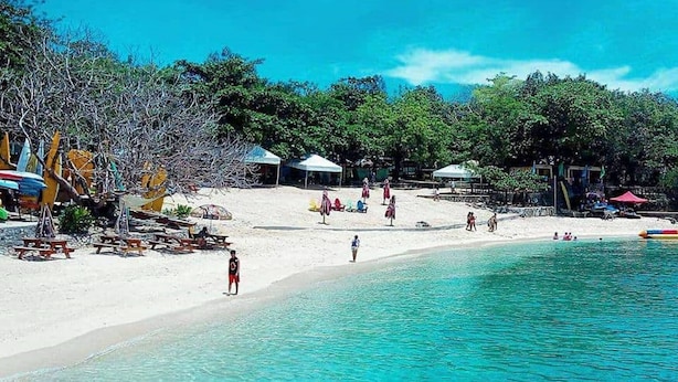 Una playa con aguas turquesas cristalinas, arena blanca y sombrillas.