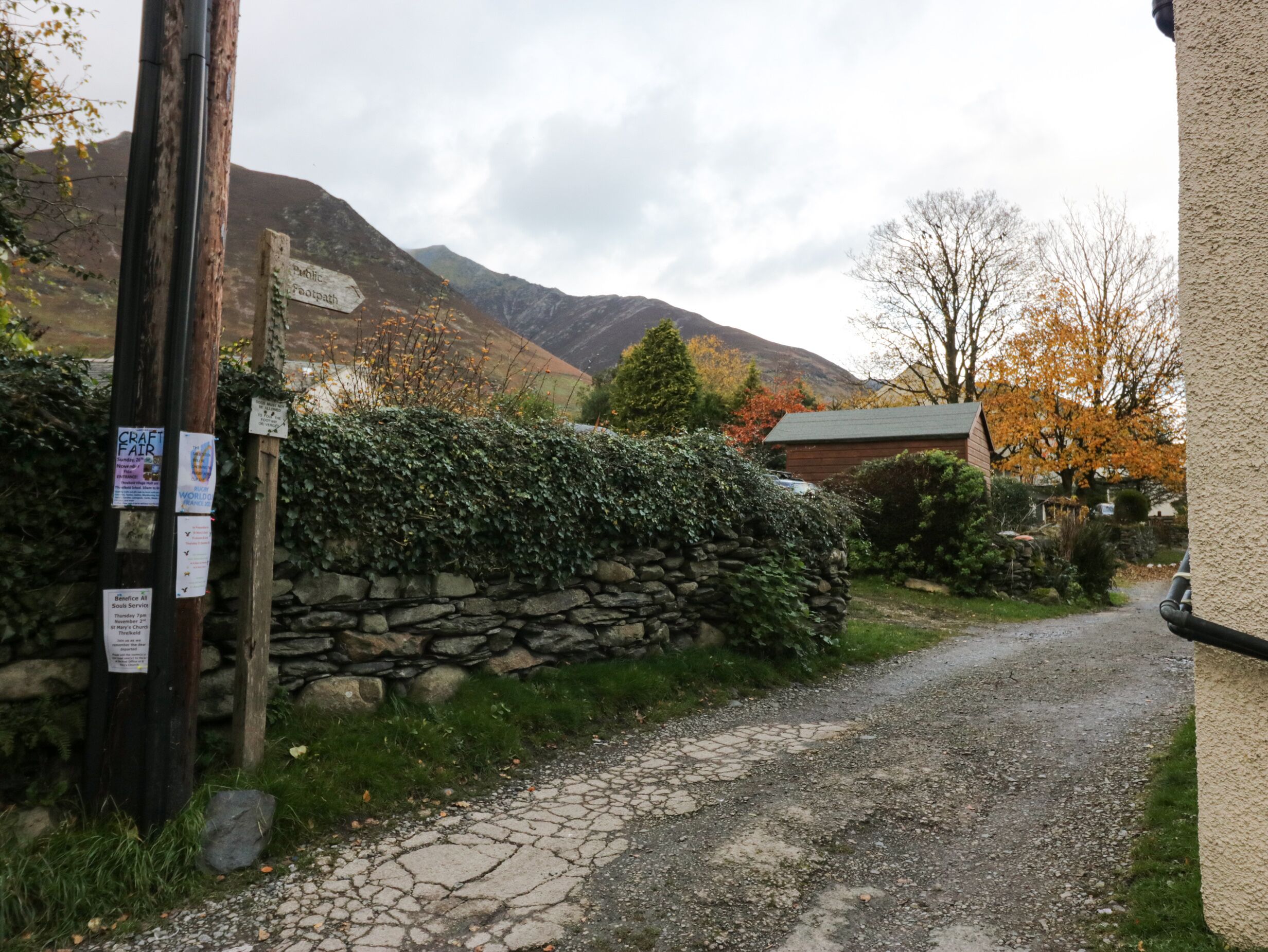 A rural road with stone walls and a wooden fence.