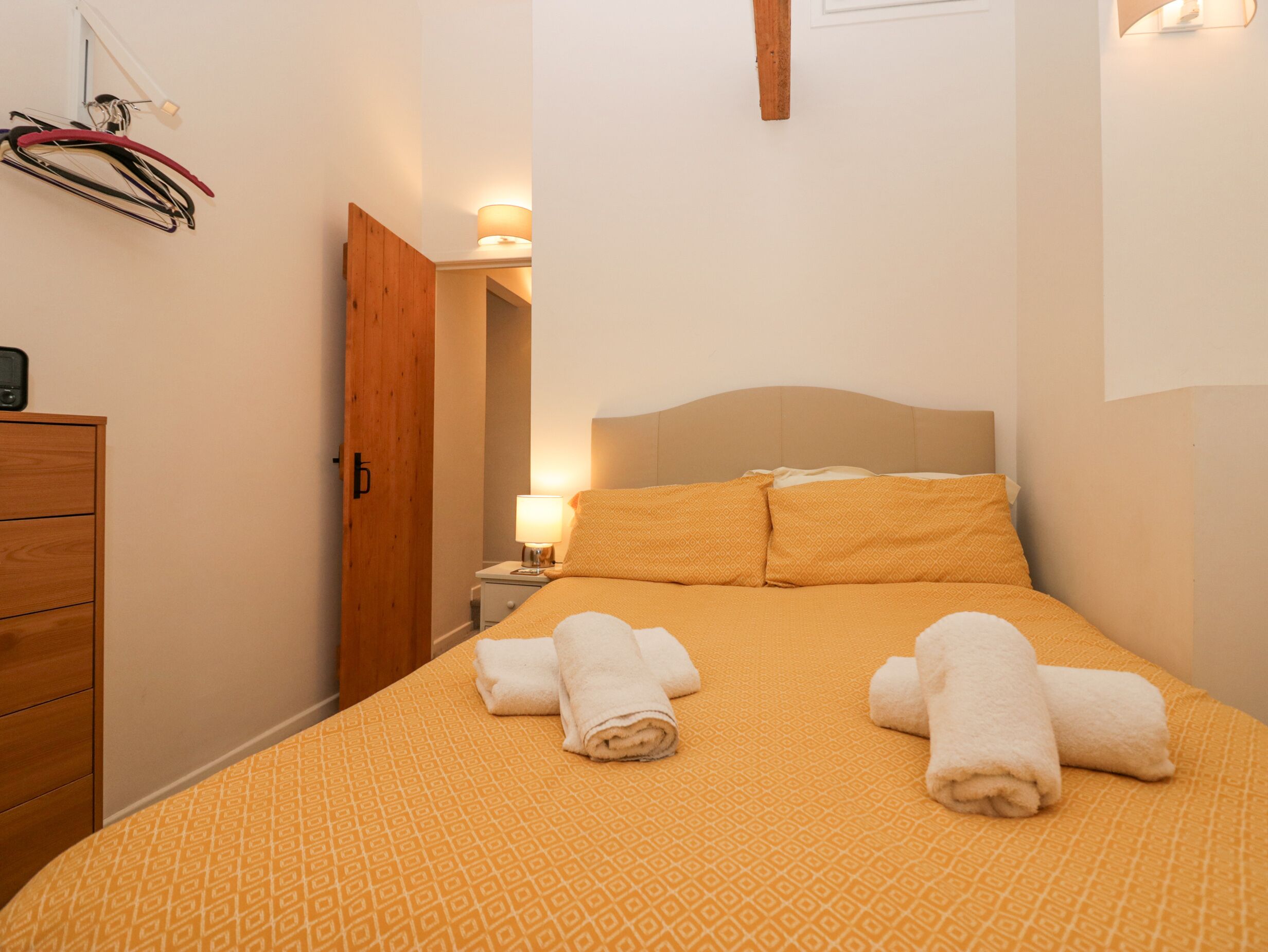 A hotel room with a bed, a nightstand, a lamp, and a wooden wardrobe.