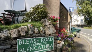 A stone wall with a green sign reading "BLEASE ROAD LEADING TO BLENCATHRA." - Taylor's Cottage (Keswick)
