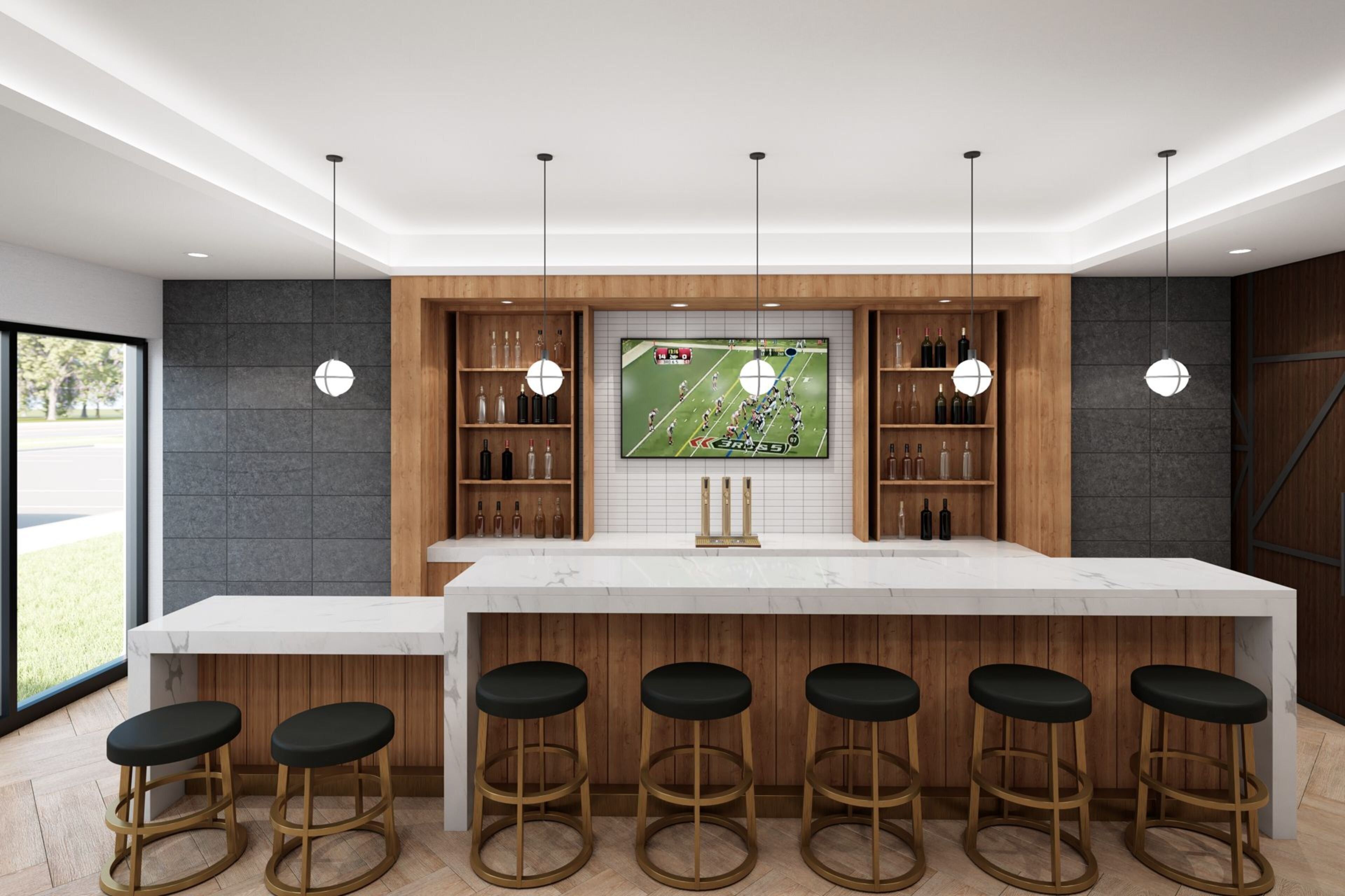 Een moderne keuken met een groot schiereiland, barstoelen en een televisie boven het schiereiland waarop een sportwedstrijd te zien is.