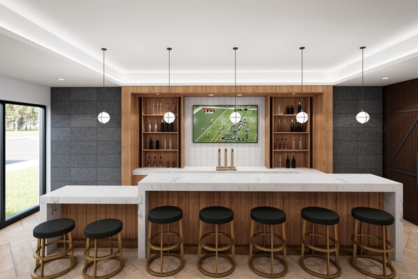 A modern kitchen with a large island, bar stools, and a TV mounted above the island displaying a sports game.