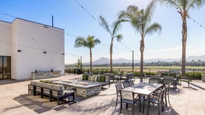 Un patio al aire libre con un hogar a leña de piedra, asientos y una parrilla.
