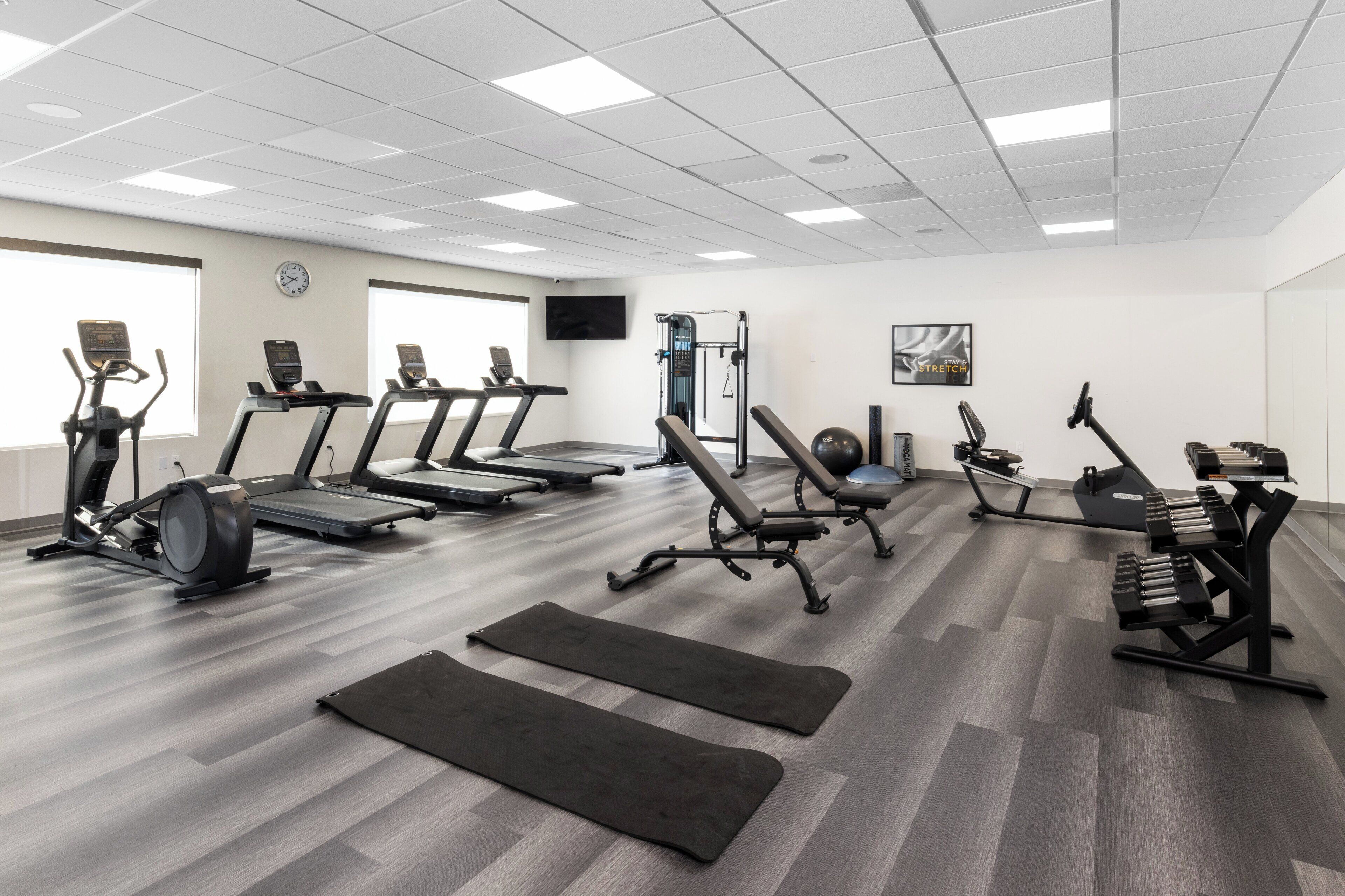 A gym with treadmills, elliptical machines, and weightlifting equipment.