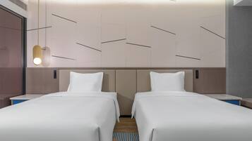 Ein Hotelzimmer mit zwei Betten, einer modernen Lampe und einer Wand mit Muster.