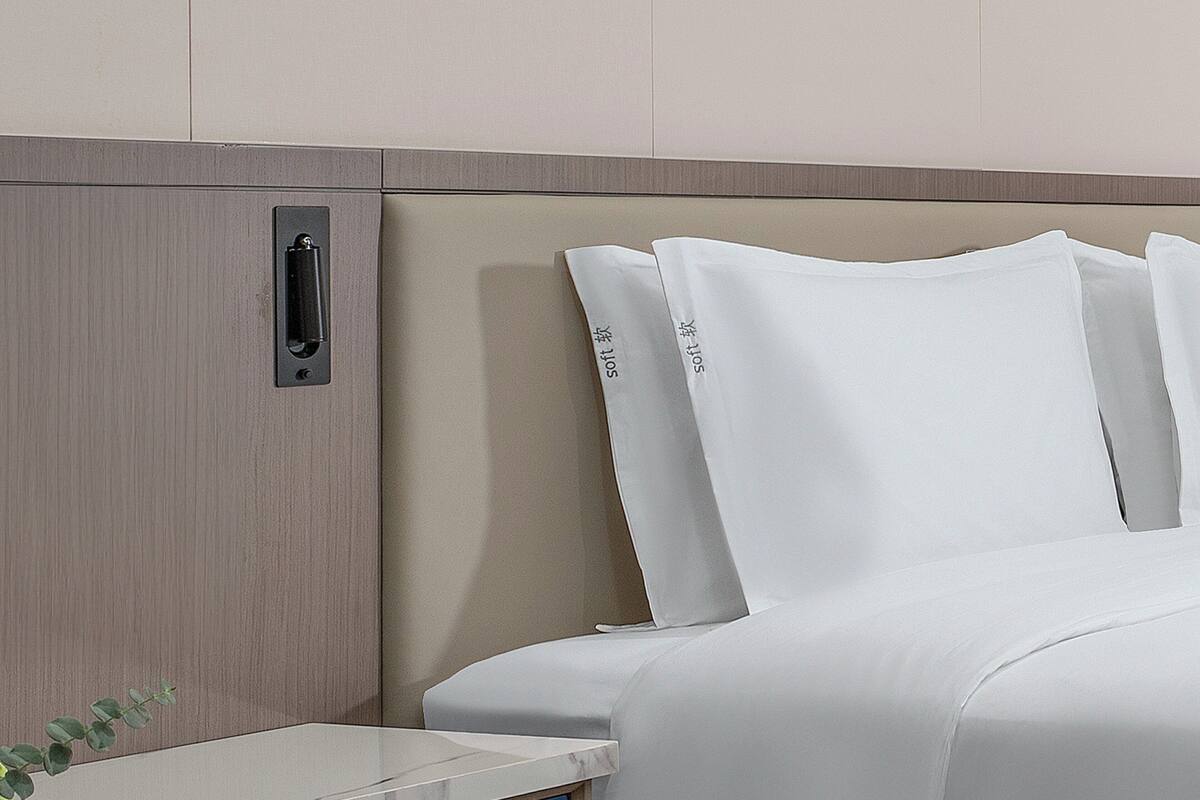 A hotel room with a bed, a nightstand, and a wooden panel wall.