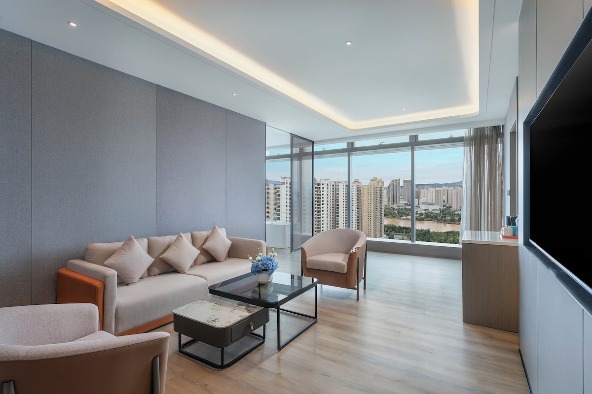 Una sala de estar moderna con sofá, sillones, una mesita de centro y una televisión grande.