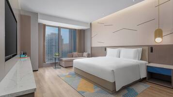 A modern hotel room with a large bed, a TV, a sofa, and a city view.