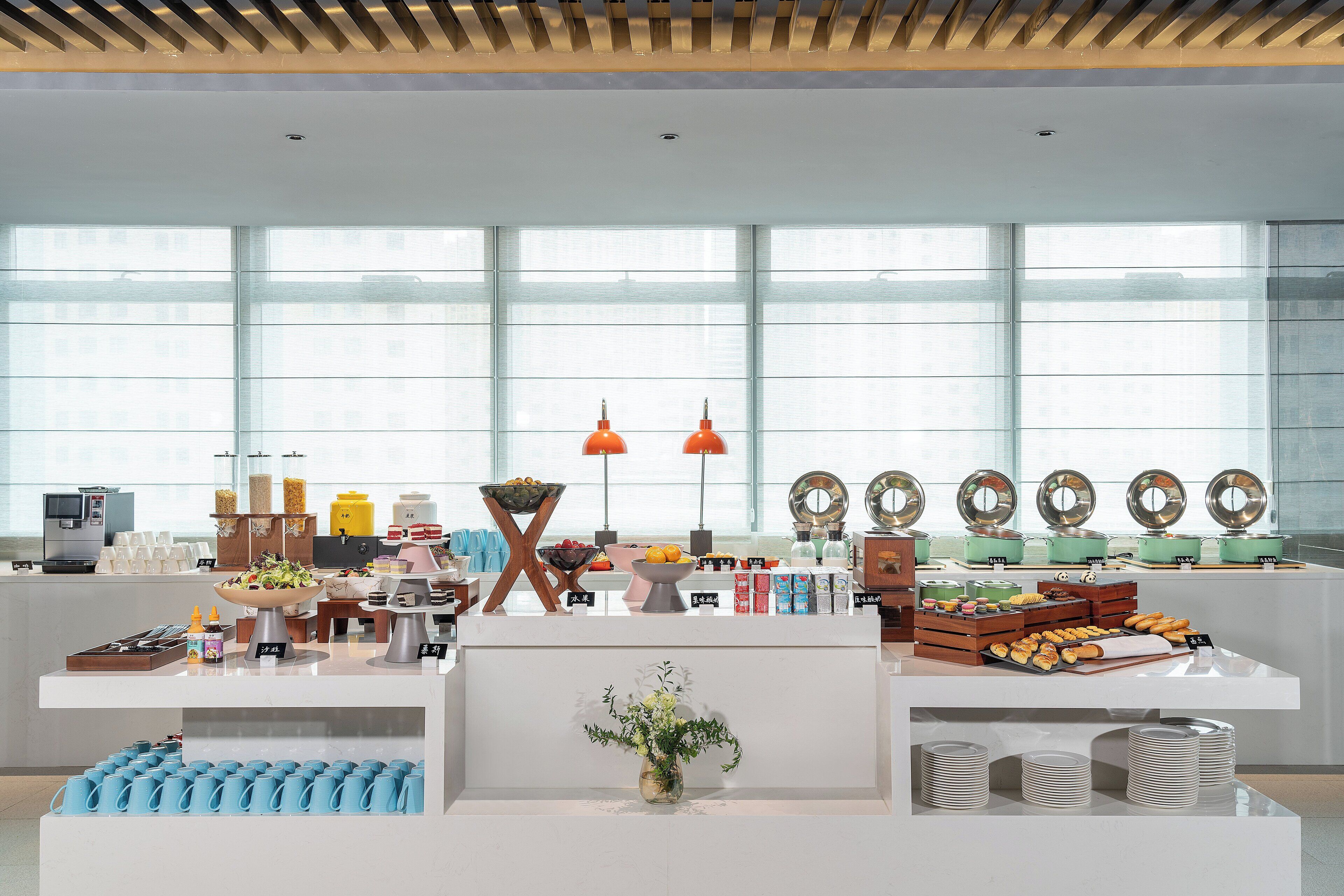 Een modern ontbijtbuffet met diverse soorten eten en een groot raam op de achtergrond.