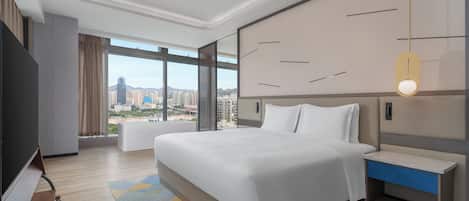 A modern hotel room with a large bed, a bedside table with a drawer, a TV, and a large window offering a city view.
