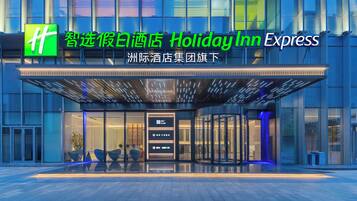 Entrada de un hotel Holiday Inn Express con diseño moderno, puertas de vidrio y fachada bien iluminada.