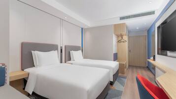 Habitación de hotel con dos camas, televisión, escritorio y baño.