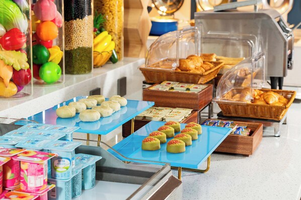 A buffet with various food items including fruits, pastries, and packaged goods.