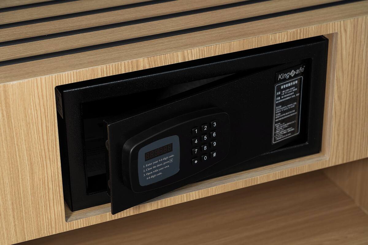 Un teclado electrónico negro con pantalla digital e instrucciones de uso, integrado en un mueble de madera.