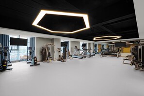 A modern gym with various exercise equipment, large windows, and geometric ceiling lights. - voco Xi'An Qindu Legend by IHG (Xi'an)