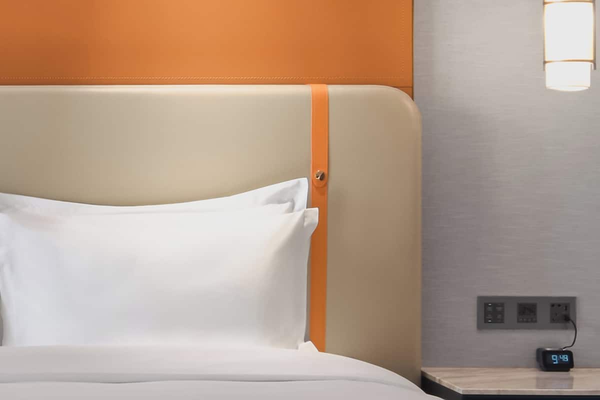 Et hotelværelse med en seng, et natbord og en lampe på væggen.