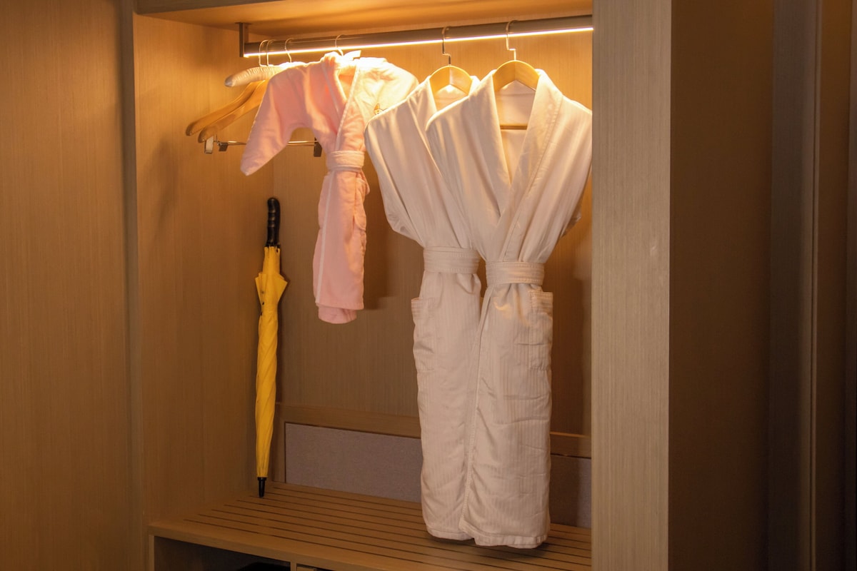 A wooden closet with hanging robes and an umbrella.