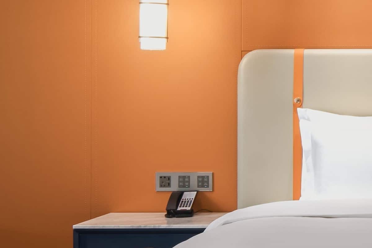 Et hotelværelse med en seng, et natbord med telefon og en stikkontakt.