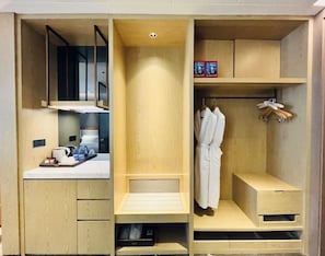 A modern, multi-functional room with a built-in desk, a robe hanging rack, and a small seating area. - voco Xi'An Qindu Legend by IHG (Xi'an)