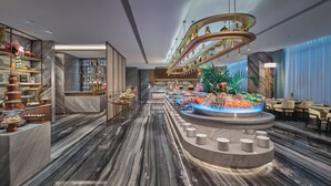 Un hall d’hôtel moderne doté d’une fontaine centrale, d’un sol en marbre et de nombreux équipements, notamment un bar et des espaces de détente.