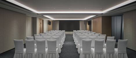 A conference room with rows of white chairs and a carpeted floor.