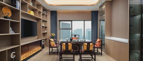 A modern dining area with a table set for four, surrounded by wooden chairs with cushions.