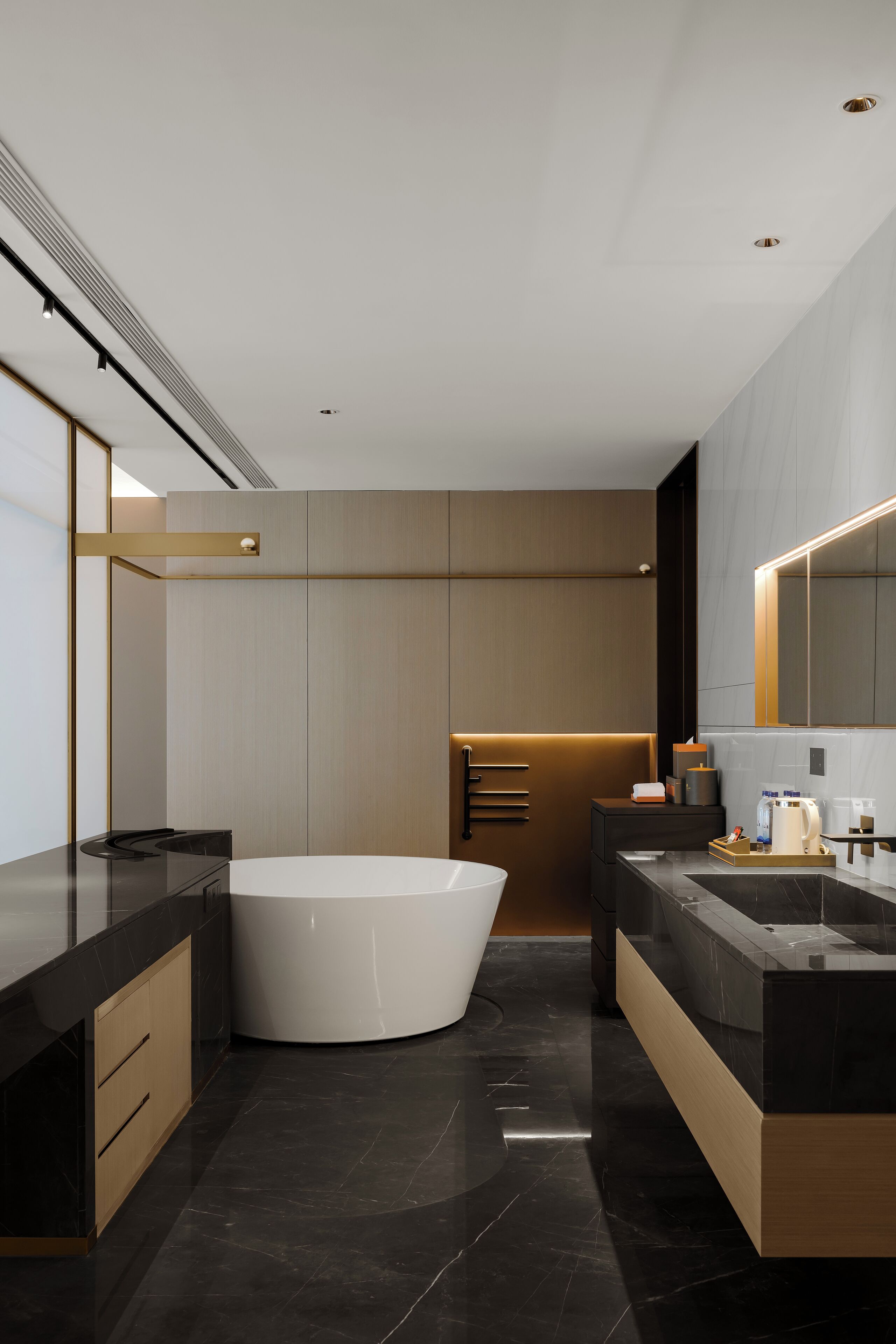 A modern bathroom with a freestanding bathtub, dark countertops, and a large mirror.