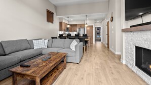 A modern living room with a gray sectional sofa, a wooden coffee table, and a fireplace.