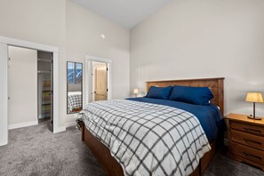 Relax in this inviting bedroom with a large bed, wooden headboard, and comfortable bedside table.