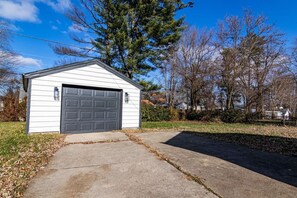 A single-story shed with a garage door, surrounded by a lawn and trees. - Hamilton Modern Organic 3Bed 3Bath Noblesville (Noblesville)