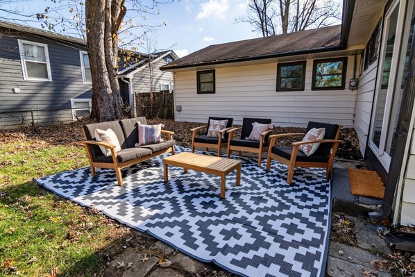 A patio area with a sofa set, two armchairs, and a coffee table, all arranged on a patterned rug. - Hamilton Modern Organic 3Bed 3Bath Noblesville (Noblesville)