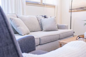 A living room with a grey sofa, a wooden coffee table, and a painting on the wall. - Hamilton Modern Organic 3Bed 3Bath Noblesville (Noblesville)