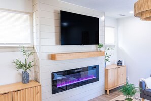 Una sala moderna con un televisor de pantalla plana montado sobre una chimenea con frente de vidrio.