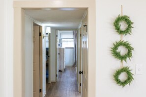 A hallway with a door on the left and a light switch on the right.