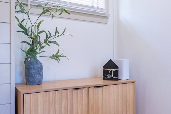 Un mueble de madera con una planta en maceta y un letrero con forma de casa que dice 'Welcome'.