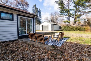 Una casa con patio, que incluye mesa y sillas, un garaje y un cobertizo.
