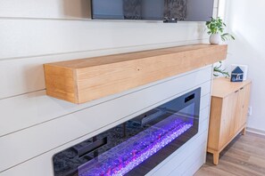 Ein moderner Kamin mit Glasfront und einem Holzboden darüber.