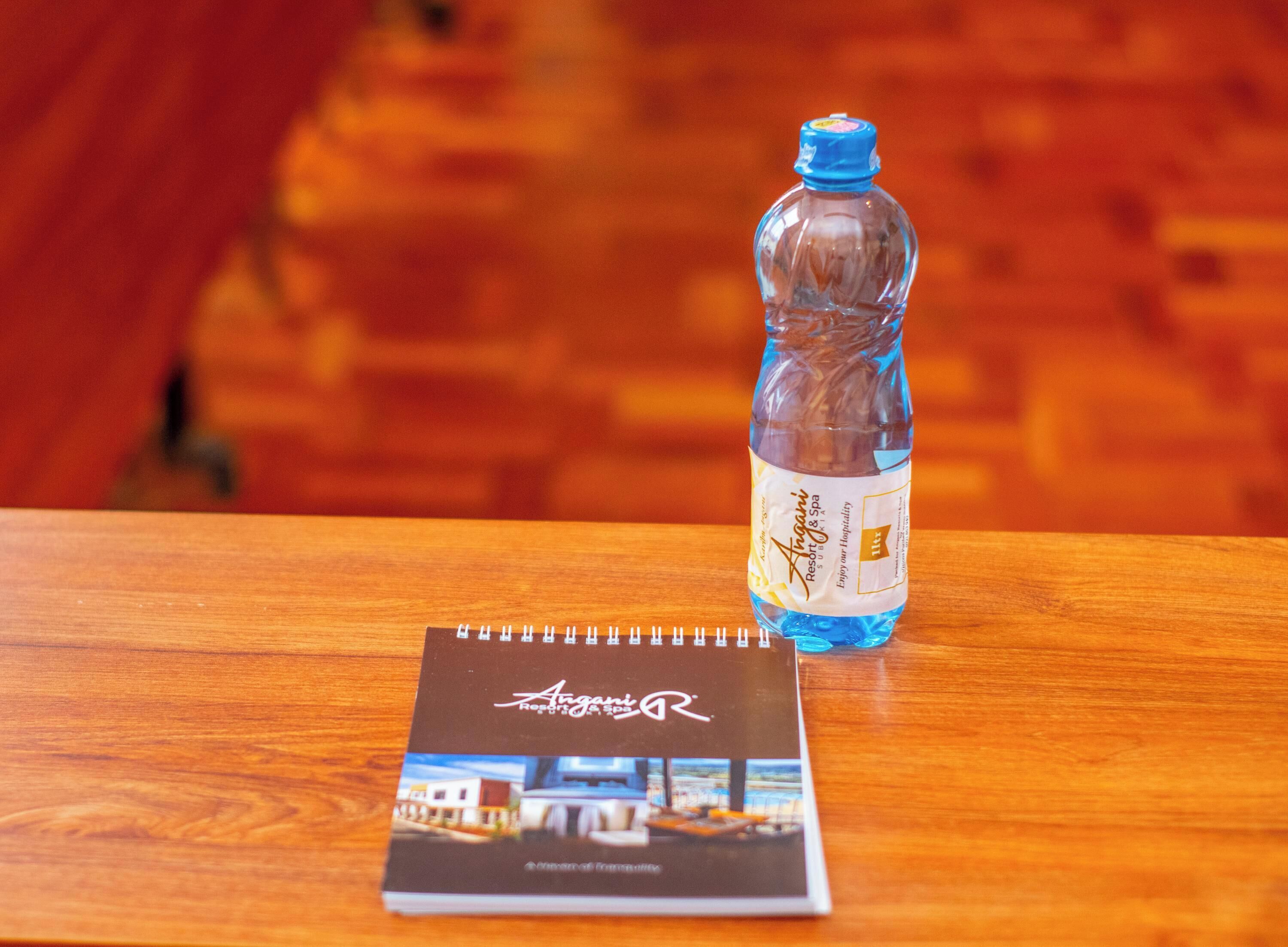A brochure and a water bottle on a wooden table.
