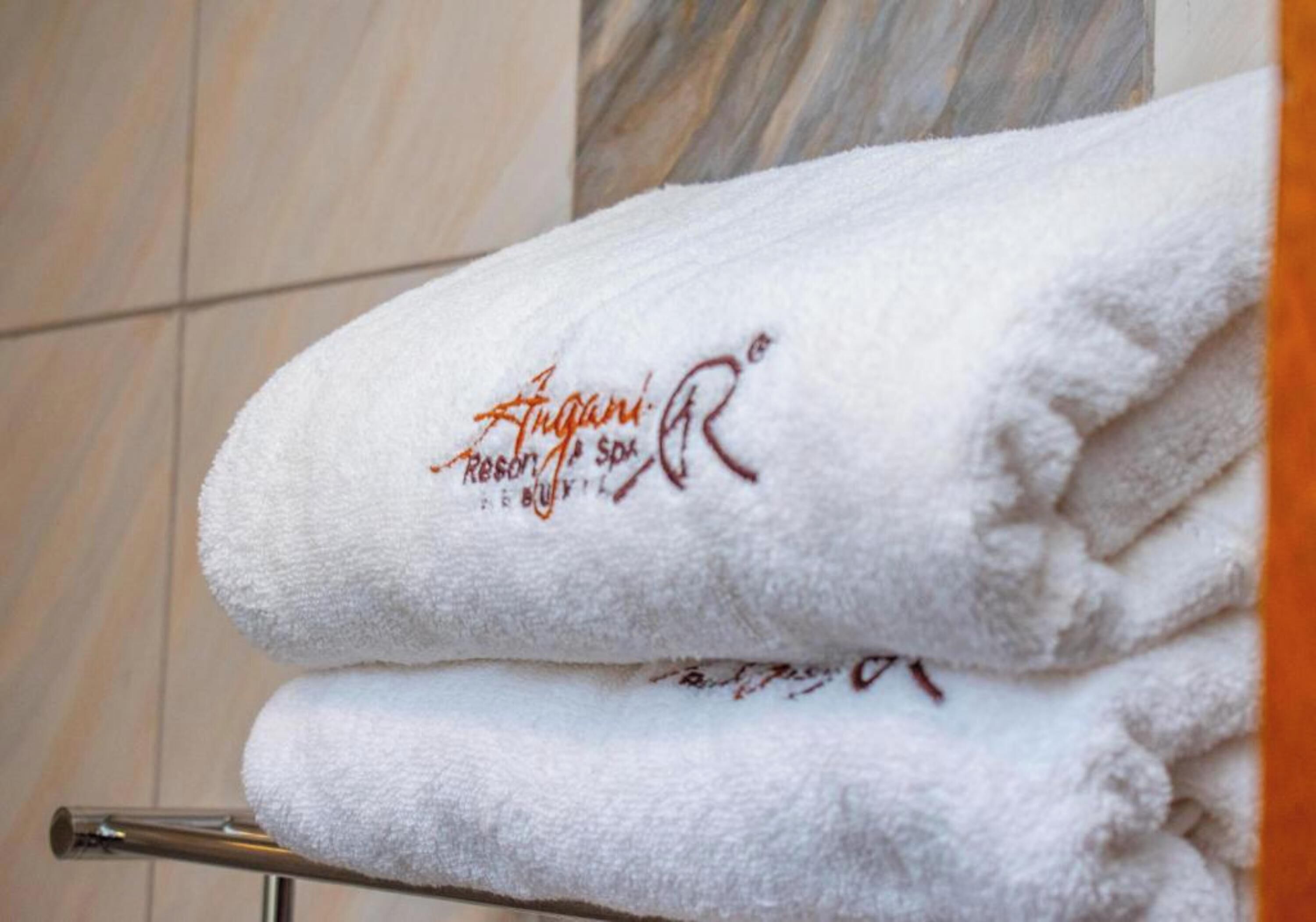 A stack of white towels with embroidered text on a metal towel rack.