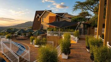 A hotel with a pool, outdoor seating, and a view of the mountains.